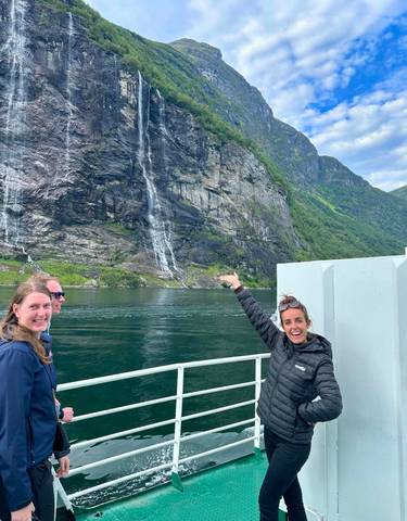 People on a boat with a scenic waterfall in the background.