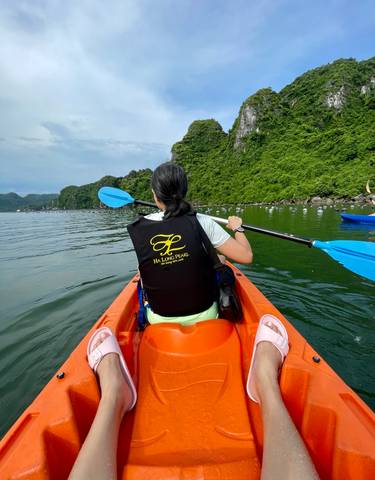 Person kayaking in a body of water with lush green hills in the background.