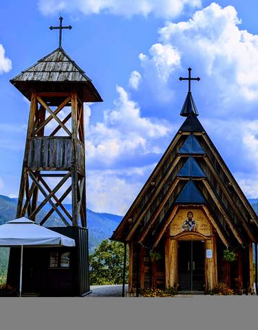 Wooden church with a bell tower against a cloudy sky.