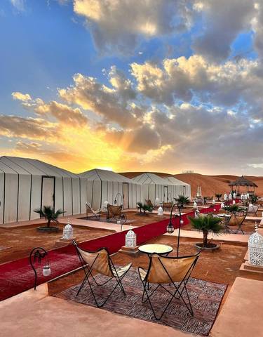 Luxury tent camp at sunrise with colorful sky.