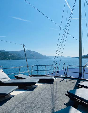 View from a boat deck overlooking a serene waterbody with mountains.