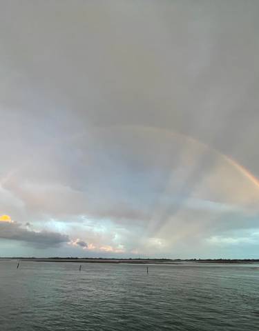A rainbow over a body of water during cloudy weather.