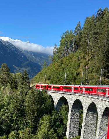 Red train on a scenic mountain route.