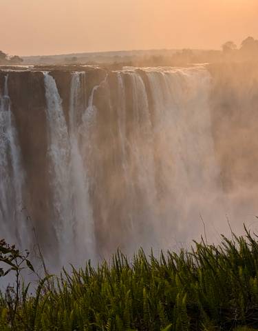 Waterfall cascading over a wide cliff with mist rising.