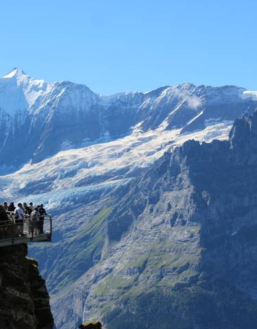 Tourists on a viewing platform with a mountain backdrop.