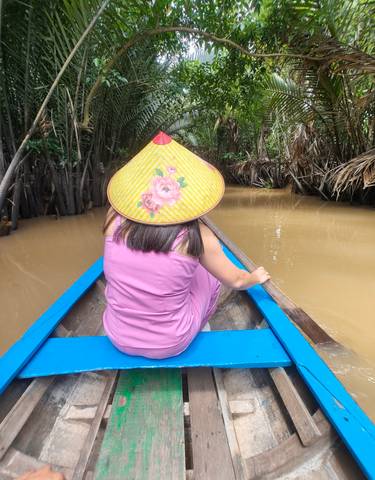 Person in a boat navigating through a river surrounded by lush greenery.