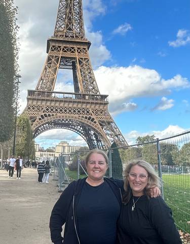 Two people standing in front of the Eiffel Tower.