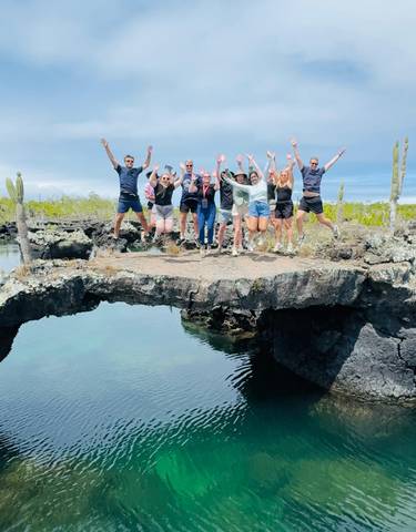A group jumps on rocky terrain with cacti around.