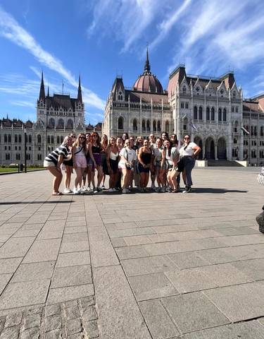 Large group posing in front of a significant historical building.