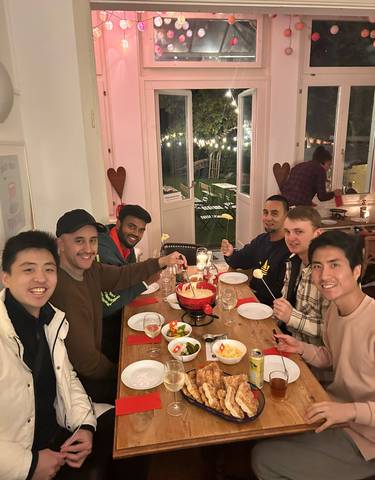 Group of friends enjoying a cheese fondue meal indoors.