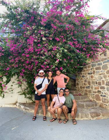 Group of people posing in front of vibrant pink flowers.