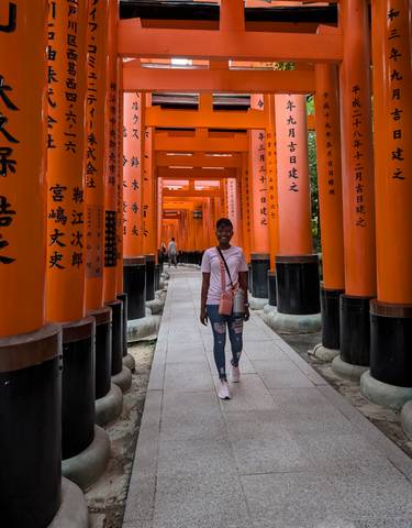 Person walking through red torii gates at Fushimi Inari Shrine