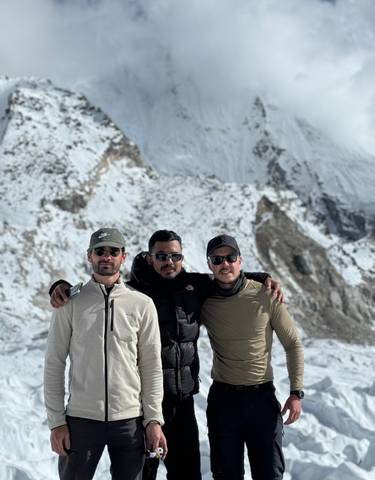 Three friends on a snowy mountain peak.