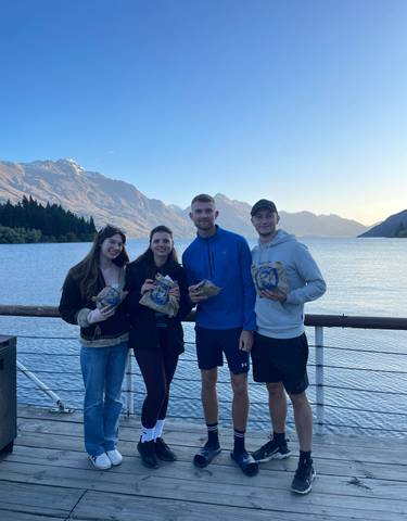 Four people enjoying snacks with a beautiful lake in the background.