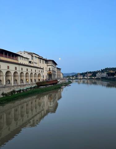 River view with historical buildings and a moon in Florence.