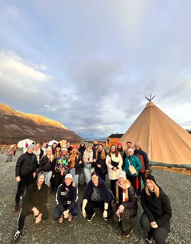 Group photo in front of a large tent in mountainous area.