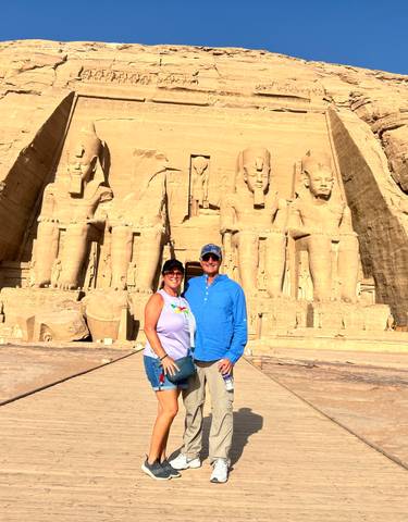 Two people posing in front of ancient temple statues.