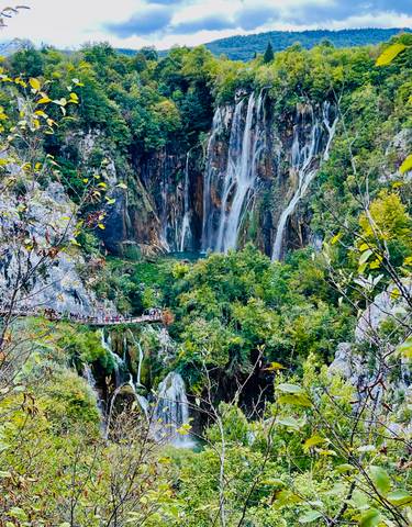 Waterfall cascading down cliffs into lush greenery.