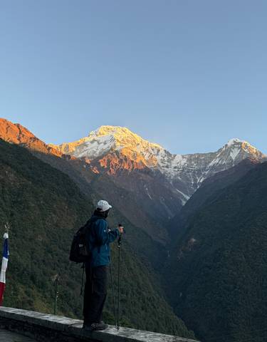Person looking at snow-capped mountains during sunrise.