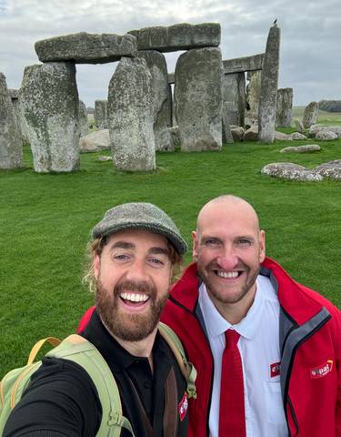 Two men posing in front of the iconic Stonehenge.
