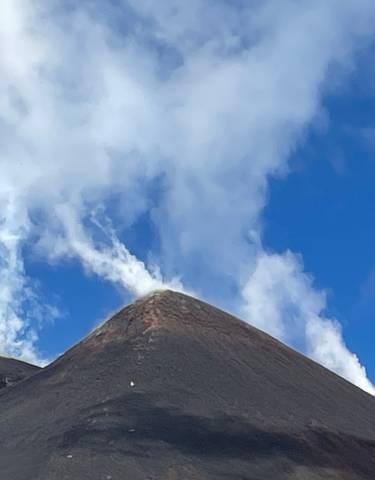 Smoking peak of a volcanic mountain under a clear sky