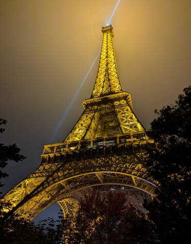 Illuminated Eiffel Tower at night with a searchlight