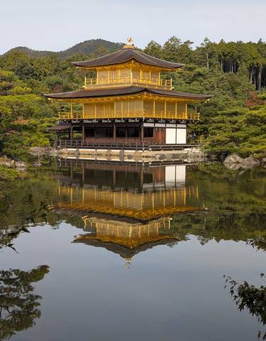 Golden pavilion reflected in a pond surrounded by gardens.