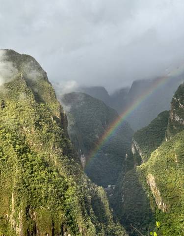 Vibrant rainbow arching over lush green mountains.