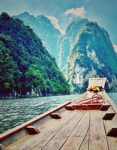 A boat on a river surrounded by lush cliffs.