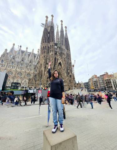 A person posing in front of the Sagrada Familia in Barcelona.