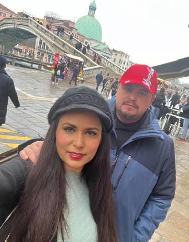 Two people posing in an urban area with crowds in the background.