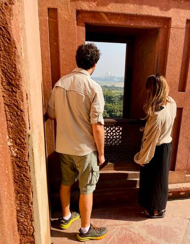 Couple enjoying a view from a historic building overlooking the Taj Mahal.
