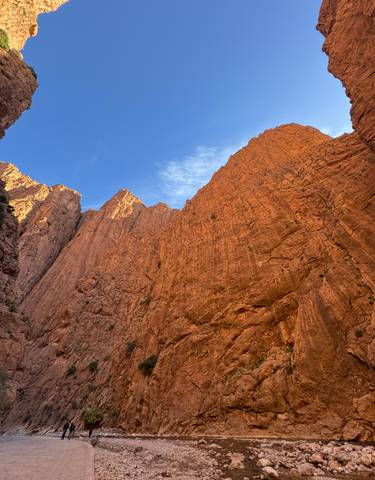 Tall rocky red cliffs rising into a blue sky.