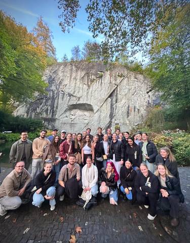Group of people in front of the Lion Monument, carved into the cliffside.
