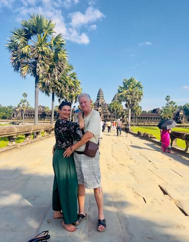 A couple posing on a stone pathway with Angkor Wat in the background.