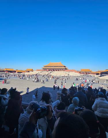 A large plaza with crowds gathered in front of historic Chinese architecture.