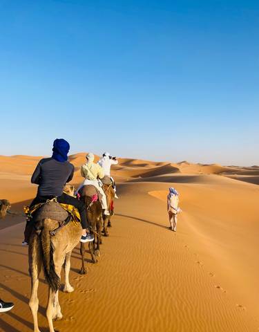 People riding camels in the desert.