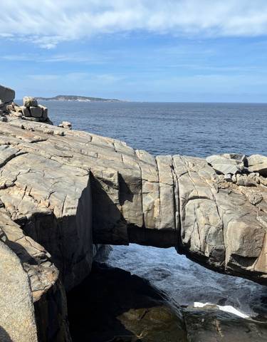 Rocky coastline with natural arch formation jutting into the sea.
