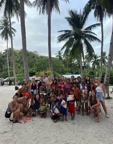 Large group photo on a beach with children and locals.