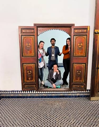 Group of people posing in front of ornate wooden doors.