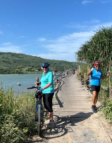 Two cyclists on a wooden bridge next to water