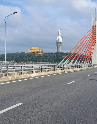 Cyclist on a bridge with modern architecture and a view of statues.