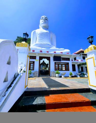 White Buddhist temple with large staircase and colorful decorations.