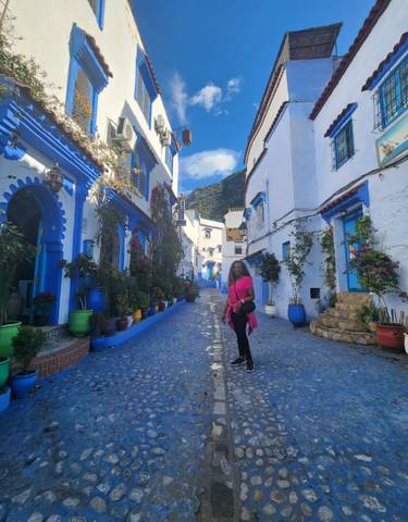 Street view with blue buildings and a woman in a bright pink outfit.