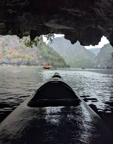 People rowing boats on a river through a picturesque valley.