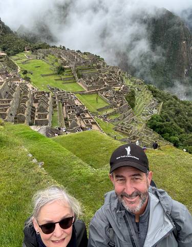 Couple smiling with Machu Picchu ruins in the background.