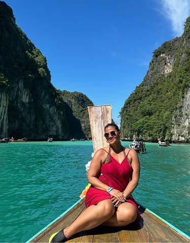 Person on a boat surrounded by stunning limestone cliffs and blue waters.