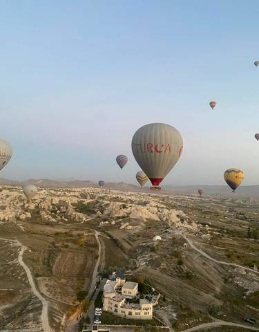 Hot air balloons over Cappadocia's rocky landscape.