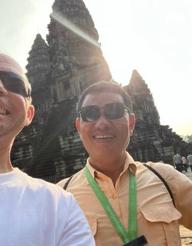 Two people smiling in front of an ancient temple.