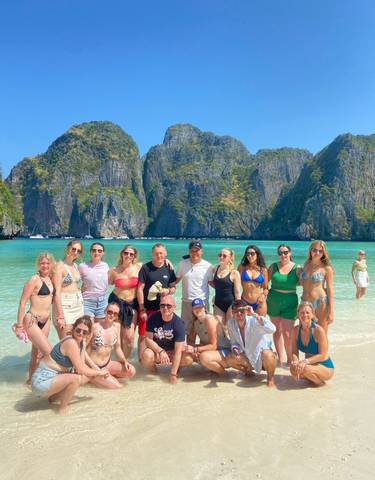 Group of people enjoying the beach with limestone cliffs in the background.
